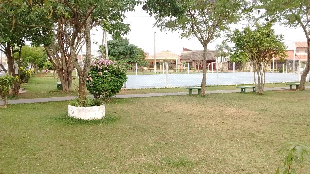 Praça arborizada do Parque Fehr com a quadra ao fundo